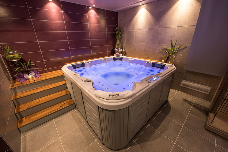 Espace bien-être avec spa encastré, éclairage indirect, marches en bois et carrelage grand format, ambiance intime et contemporaine à Alès